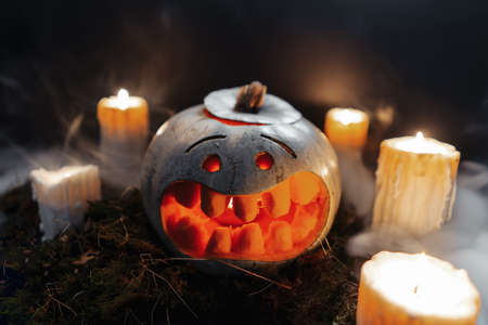 Carved Halloween pumpkin on dark background with enlighted candles.の写真素材