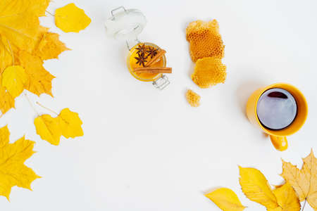 Autumn composition flat lay. Cup of tea, dried leaves, honey jar, wax cells, cinnamon sticks and...