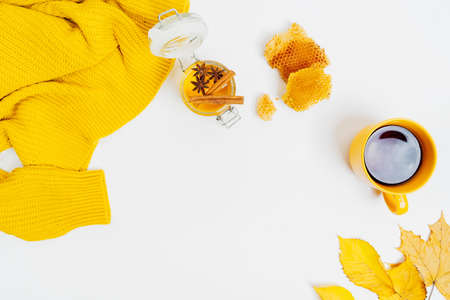 Autumn composition flat lay. Cup of tea, women fashion sweater, dried leaves, honey jar, wax cells,...