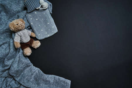 Flat lay of rubber hotty warmer and bear toy on sweater. Winter time concept.の写真素材