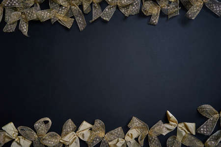 Flat lay of golden gift bows on dark background. New year and christmas eve celebration concept.