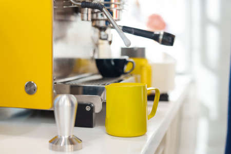 Close up of modern coffee machine and yellow pincher on bar counter.の写真素材
