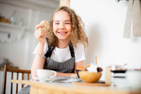 Young cute girl eating oat cookie and smiling. Family love and care concept.の写真素材