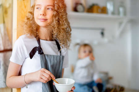 Young cute girl and her toddler sister preparing breakfast for parents.
