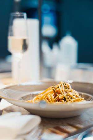 Fresh tasty italian pasta with seafoods on plate with cooled champagne glass on background.の写真素材