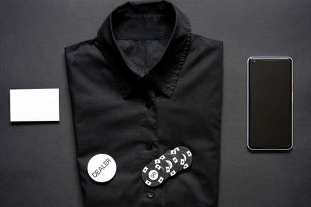 Casino chips, formal shirt, blank business card and mobile phone on minimalistic black background. Casino game. Online casino. Gambling concept, poker mobile app. Poker game theme.の写真素材