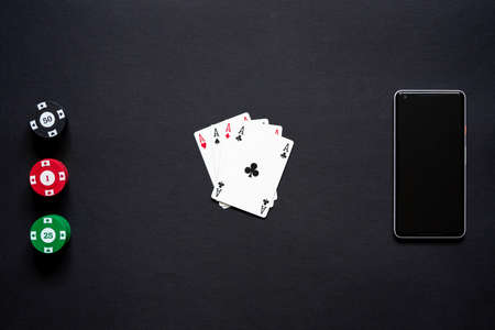Casino chips, playing cards and mobile phone on minimalistic black background. Casino game. Online casino. Gambling concept, poker mobile app. Poker game theme. set of four acesの写真素材