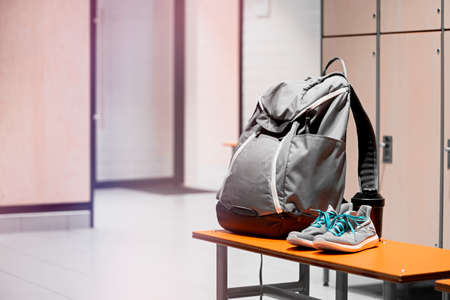 Close up of sports shoes, sport backpack and sport water bottle in gym locker room. Concept of...