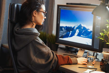 Young attractive woman freelancer designer working on pc at home. Concept of freedom and creativity. Home office. Casual dress.の写真素材