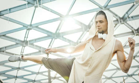 Close up of attractive athletic man practicing yoga and warming up outdoors in modern park under the glass dome.の写真素材