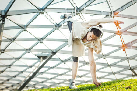 Attractive athletic man practicing yoga outdoors and warming up in modern park at green grass.の写真素材