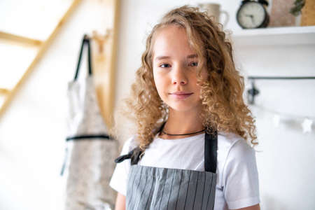 Young cute curly girl preparing breakfast for parents and smiling.の写真素材