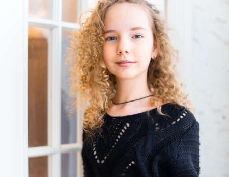 Young cute girl standing near to white door and smiling.の写真素材