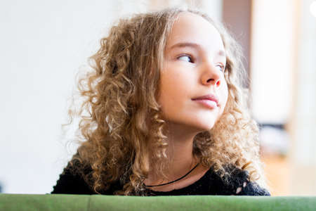 Young cute teenage girl sitting on green couch.