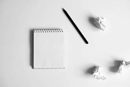 Flat lay of blank white notepad, pencil and crumpled paper on white background. Concept of inspiration and lack of ideas. Creativity.の写真素材