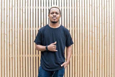 Close up of attractive dark-skinned man in black T-shirt on wooden background.の写真素材