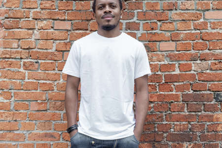 Dark-skinned man showing blank business card on red bricked background.の写真素材