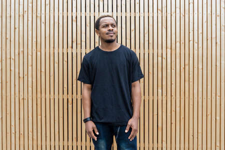 Close up of attractive dark-skinned man in black T-shirt on wooden background.の写真素材