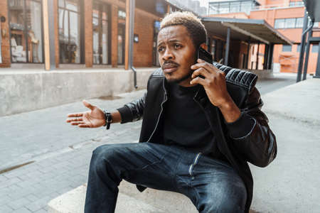 Dark-skinned unpleasantly surprised and annoyed man talking by mobile phone.の写真素材