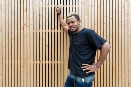 Close up of attractive dark-skinned man in black T-shirt on wooden background.の写真素材