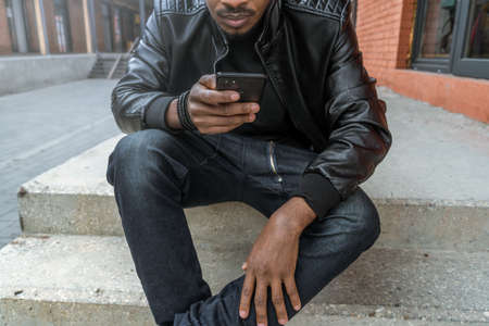 Close up of dark-skinned man looking at mobile phone screen.の写真素材