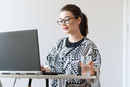 Young and pensive attractive woman working on laptop in modern bright apartments. Freelance concept. Home office.の写真素材
