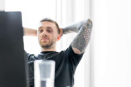 Handsome pensive man working on laptop in modern bright apartments. Home office. Freelance concept. Young entrepreneur.の写真素材
