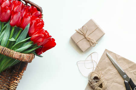 Flatlay of tullips and craft wrapping paper, ribbon, scissors and present. Summer or spring time. International women day. Copy space. Empty space.の写真素材