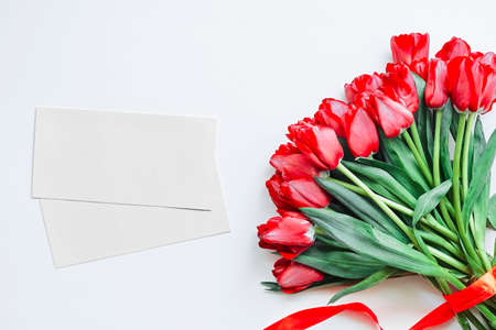 Flatlay of tulips and envelopes on white background. Summer or spring time. International women day. Copy space. Empty space.の写真素材