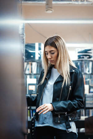 Young attractive woman choosing vinyl record in music record shop. Melomaniac or music addict...