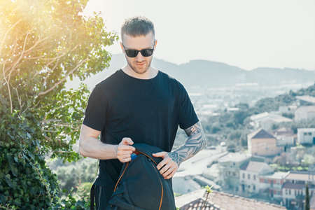 Young handsome man holding backpack on european background. Traveler and blogger.