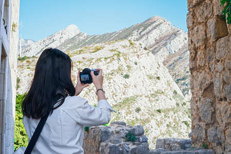 Attractive woman blogger making photos of beautiful mountain landsape in ancient european fortress. Bar Townの写真素材