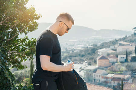 Young handsome man holding backpack on european background. Traveler and blogger.の写真素材