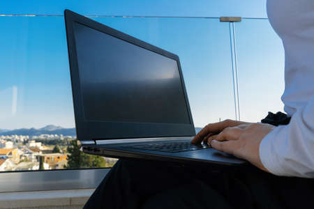 attractive woman working on laptop on balcony and enjoying beautiful landscape panorama. View on Sea, mountains and town. Freelancer work place. Connection and availability in every part of planetの写真素材