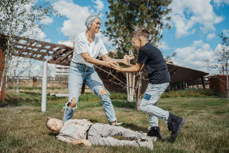 Young attractive mum having fun with her sons at green modern park. Happy family concept.の写真素材