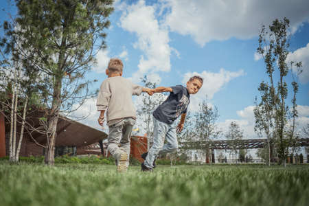 Two brothers turning around, whirling and having fun at green park. Happy family concept.の写真素材