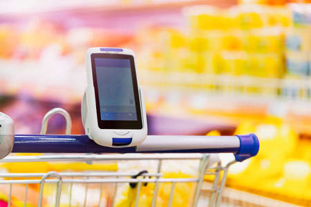 Close up of bar code scanner on shopping cart in store. Concept of modern gadgets and devices, Consumerism.の写真素材
