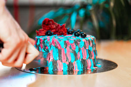 Woman cutting cake with colourful cream. Juicy filling with red berries.の写真素材