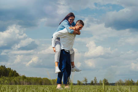 Couple of young beautiful man and woman having fun outdoors at sunny summer day. playing piggyback rideの写真素材