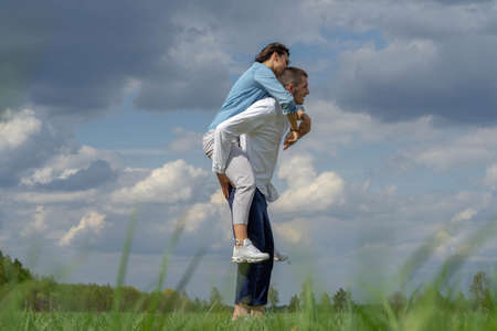 Couple of young beautiful man and woman having fun outdoors at sunny summer day. playing piggyback rideの写真素材