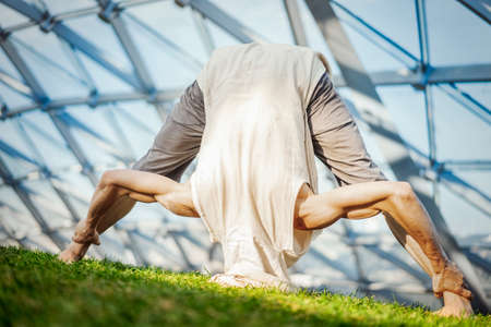 Close up of attractive athletic man practicing yoga and warming up outdoors.の写真素材