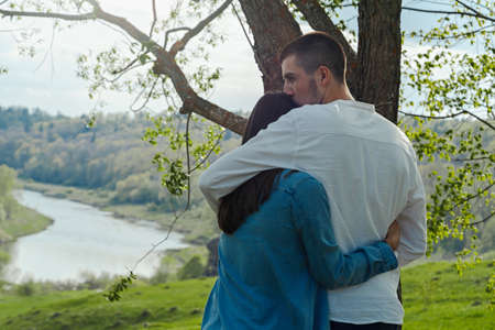 Couple of young beautiful man and woman hugging outdoors at sunny summer day at beautiful landscape background at countryside.の写真素材
