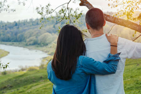 Couple of young beautiful man and woman hugging outdoors at sunny summer day at beautiful landscape background at countryside.の写真素材