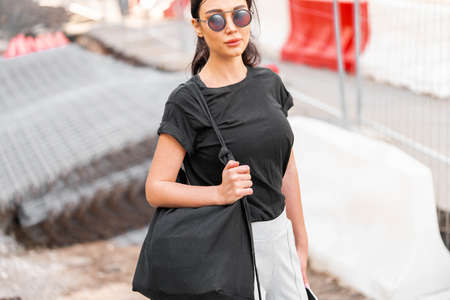 Young attractive woman in black blank t-shirt outdoors. Empty space. Copy space.の写真素材