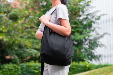 Woman with black blank bag outdoors in park. Empty space. Copy space.の写真素材