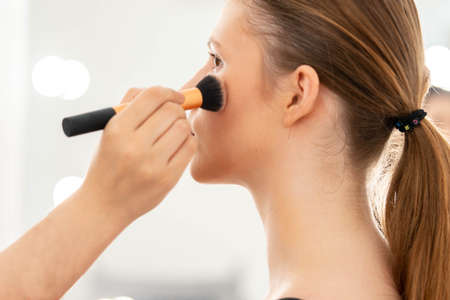 Hand of Make up artist applying powder or painting model cheeks with brush.の写真素材