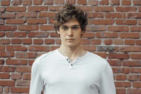 Close up of young attractive man standing on red brick background. Model male posing.の写真素材