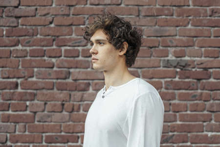 Close up of young attractive man standing on red brick background. Model male posing.の写真素材