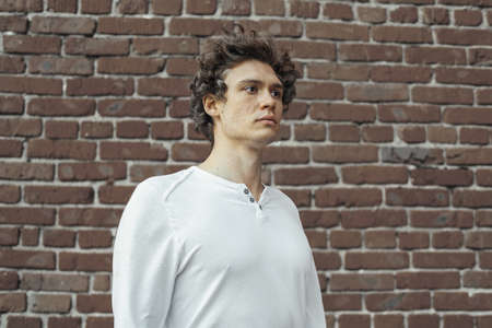 Close up of young attractive man standing on red brick background. Model male posing.の写真素材