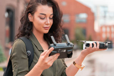 Young beautiful woman launching drone quadcopter at urban background. cityscape. modern device.の写真素材